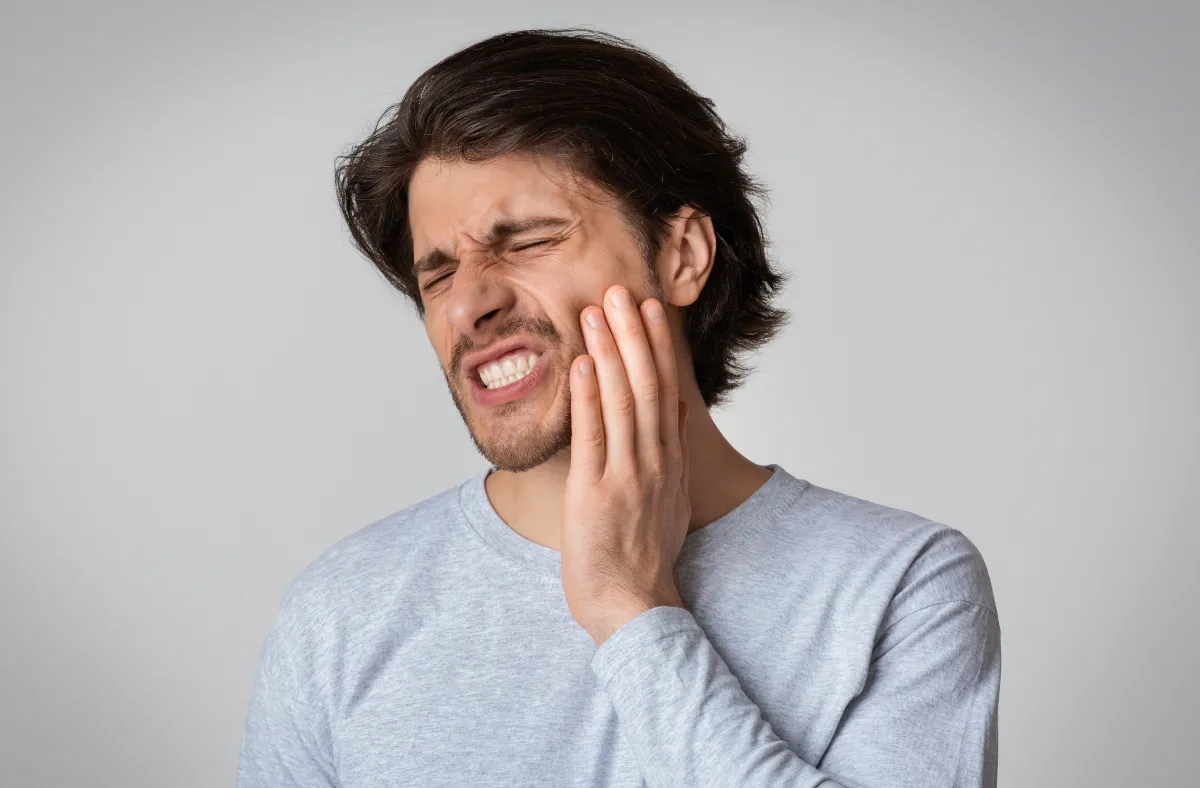 Man experiencing tooth pain, emergency dental care at Studio One Dental in Humble, TX